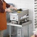 A man in an apron cooking food on a Cooking Performance Group electric countertop griddle.