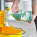 A hand pouring Noble Eco Step and Shine floor cleaner into a yellow container.