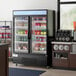 A Main Street Equipment swing glass door merchandiser refrigerator with drinks inside.