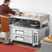 A man in an orange apron using a Cooking Performance Group electric countertop griddle.