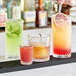 A bartender pouring drinks into Acopa Aurelius rocks glasses on a table in a cocktail bar.