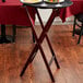 A mahogany Lancaster Table & Seating folding wood tray stand with a tray of food on it.