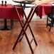 A person holding a tray of food on a Lancaster Table & Seating mahogany wood tray stand.