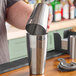 A bartender pouring a drink into a Barfly stainless steel cocktail shaker.