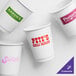 A close up of a white customizable paper hot cup with red text.