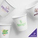 A group of white customizable paper hot cups with logos and text in different colors.