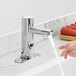 A person washing their hands in a bathroom sink with a Waterloo hands-free faucet.