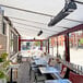 An Aura carbon black electric infrared heater on a patio table with a green plant.