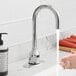 A person washing their hands under a Waterloo hands-free faucet with a gooseneck spout.