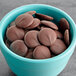 A blue bowl filled with Ghirardelli 100% Cacao unsweetened chocolate liquor wafers.