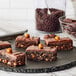 A group of Ghirardelli chocolate brownies on a black plate.