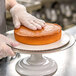 A person in gloves holding a Rich's Allen white layer cake on a plate.