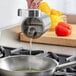 A person using a Choice stainless steel oil pourer to pour oil into a pan.