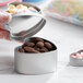 A hand holding a silver heart-shaped tin filled with chocolate candies.