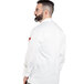 A man wearing a white Uncommon Chef long sleeve chef coat with white sleeves and back.