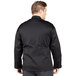 A man wearing a black Uncommon Chef long sleeve chef coat with a mesh back.