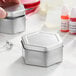 A silver hexagon-shaped metal tin with a slip cover.