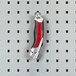 A red and black Triton Products steel tool on a pegboard hook.