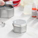 A silver hexagon-shaped metal tin with a slip cover.