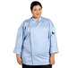 A woman wearing a sky blue Uncommon Chef long sleeve chef coat with a mesh back.