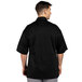 A man wearing a black Uncommon Chef Venture Pro Vent chef coat.