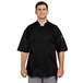A man wearing a black Uncommon Chef Venture Pro Vent chef coat.