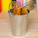 An American Metalcraft mini galvanized pail filled with fried chicken on a table in a restaurant.