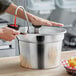 A person using a ServSense stainless steel pump to pour sauce into a bowl.