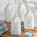 A group of white Nourish body lotion jugs with green labels next to a bowl of towels.