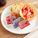 A plate with a bagel and Smucker's jelly on it.