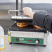 A person cooking sandwiches on a Waring Panini Supremo grill.