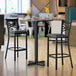 A Lancaster Table & Seating bar height table with a black base and chairs in a restaurant.