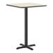 A square bar height table with a reversible white birch or ash laminated top and a black cast iron base.
