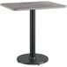 A Lancaster Table & Seating table with a black base and gray top on a black pole.