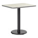 A rectangular table with a reversible gray and white laminated top and a black cast iron pedestal base.
