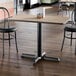A rectangular standard height table with a reversible white birch and ash laminated top and a black cast iron base.