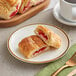 A plate with two Orange Bakery strawberry cream cheese filled croissants and a cup of coffee.