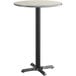 A white and gray round table top on a black pole with a black base.