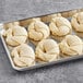 A metal tray of raw Orange Bakery curved butter croissants.