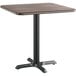 A Lancaster Table & Seating white birch and ash laminated square table top with a black base.