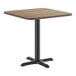 A square standard height table with a reversible white birch and ash laminated top and a black cast iron base.