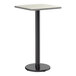 A square bar height table with a reversible gray and white laminated top and a black cast iron base.