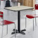 A rectangular reversible gray and white laminated table with a black cast iron base, shown with red chairs in a dining area.