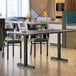 A Lancaster Table & Seating white birch and ash laminated table and base with a chair and cup on it.