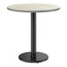 A round standard height table with a reversible gray or white laminated top and a black cast iron pedestal base.