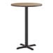 A round bar height table with a reversible white birch or ash laminated top and a black cast iron base.