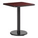 A square standard height table with a reversible cherry and black laminated top and a round cast iron base.