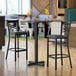 A black table with a reversible cherry/black laminated top on a table with chairs and a plant.