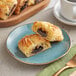 A plate with two Orange Bakery ready to bake chocolate filled croissants and a cup of coffee on a table.