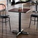 A square, reversible cherry and black laminated restaurant table with a black cast iron base.